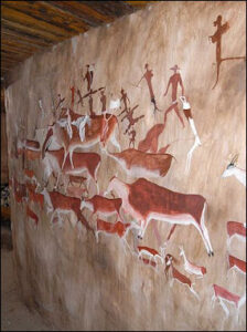 Ancient rock art depicting red and white painted figures of people and animals on a cave wall in South Africa