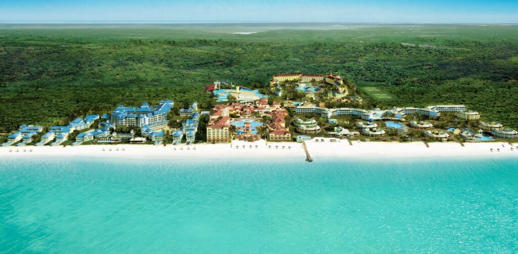 Aerial view of Beaches Turks and Caicos resort with colorful buildings, pools, and white sand beach along turquoise water