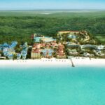Aerial view of Beaches Turks and Caicos resort with colorful buildings, pools, and white sand beach along turquoise water