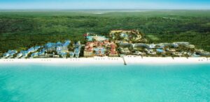 Aerial view of Beaches Turks and Caicos resort with colorful buildings, pools, and white sand beach along turquoise water