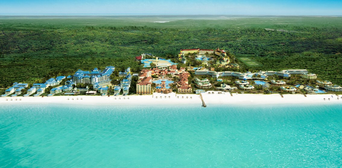 Aerial view of Beaches Turks and Caicos resort with colorful buildings, pools, and white sand beach along turquoise water